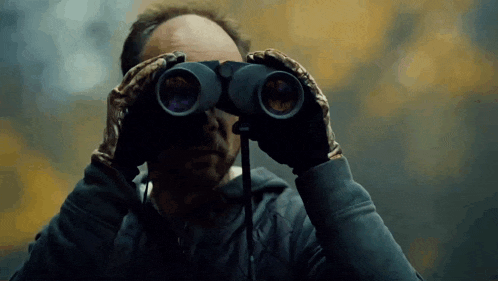 a man in gloves is looking through binoculars .