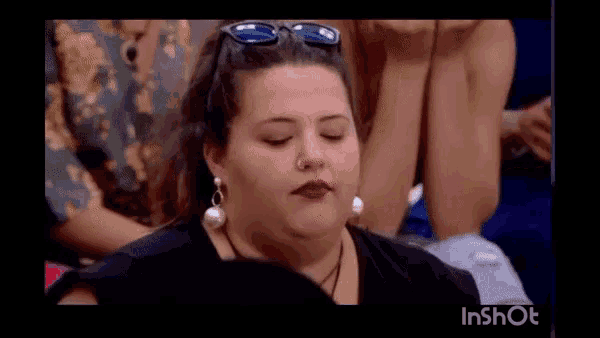 a woman wearing sunglasses and earrings is making a funny face while sitting in a audience .