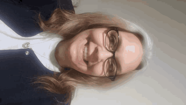a woman wearing glasses and a black jacket smiles
