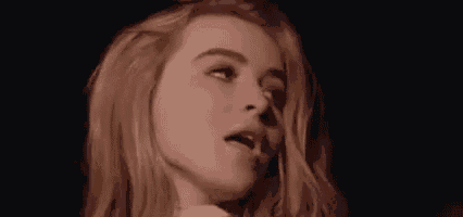 a close up of a woman blowing a kiss in a dark room .