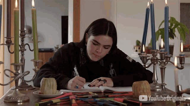 a woman sits at a table with candles and a youtube logo