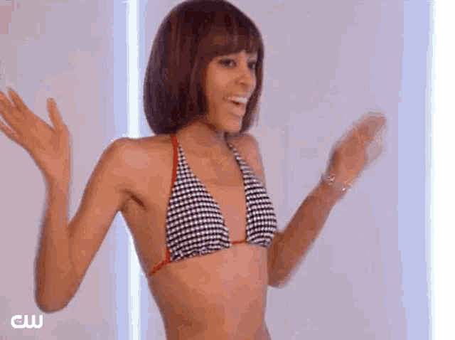 a woman in a bikini is dancing with her arms outstretched and smiling .