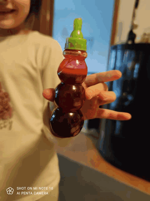 a shot on mi note 10 shows a child holding a bottle of liquid