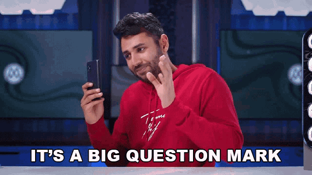 a man in a red hoodie is holding a cell phone and says " it 's a big question mark "