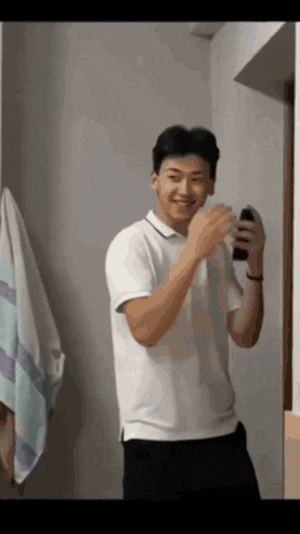 a man in a white shirt is smiling and holding a bottle in his hand