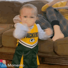 a baby wearing a green bay packers jersey