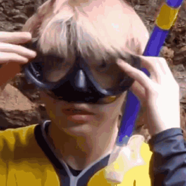 a person wearing a yellow shirt is adjusting their diving goggles