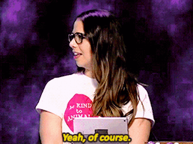 a woman wearing glasses and a kind to animals shirt says " yeah of course "