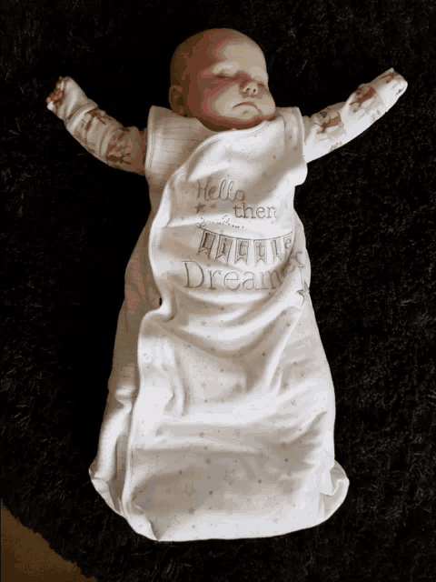 a baby is wrapped in a white sleeping bag that says hello then little dreamer