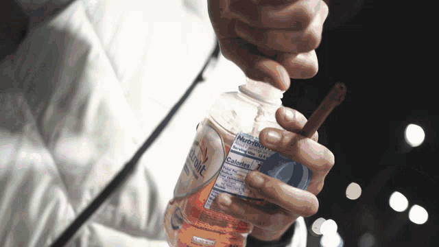 a person is pouring water into a bottle that says nutrition facts