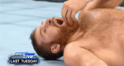 a shirtless man is laying on the ground with his mouth open in front of a smackdown live banner
