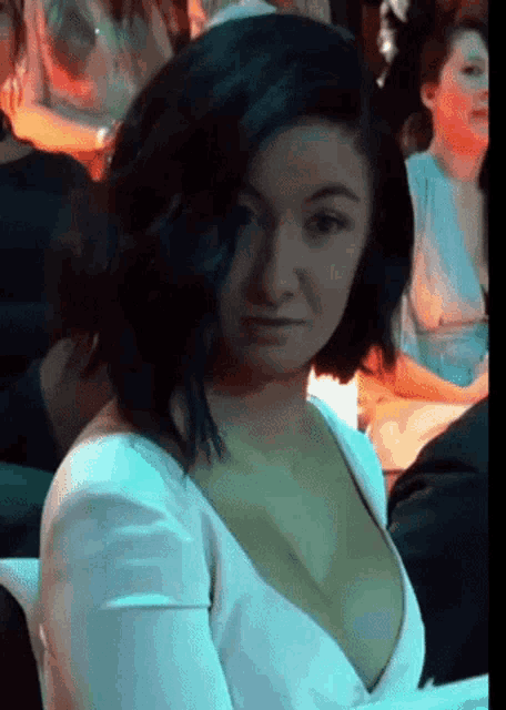 a woman in a white dress is sitting in a crowd .