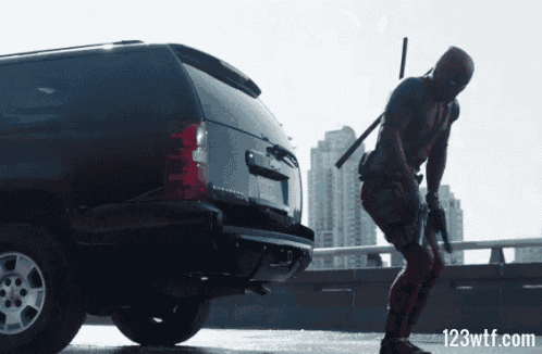 a picture of deadpool standing next to a suv with 123wtf.com on the bottom