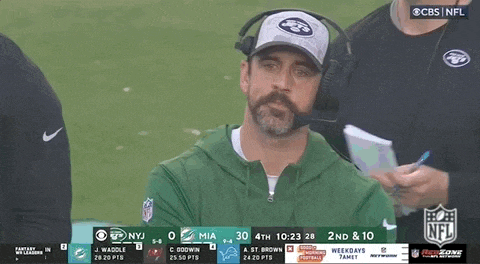 a man with a beard is wearing a hat and headphones while watching a football game on cbs .