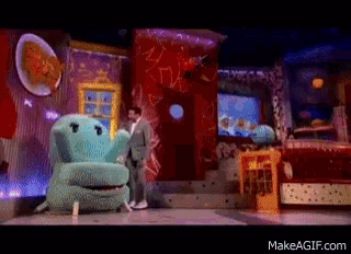 a man in a suit stands next to a stuffed animal that looks like a hippo