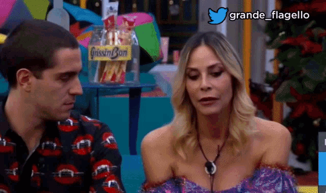 a man and a woman are sitting next to each other with a sign that says grande flagello