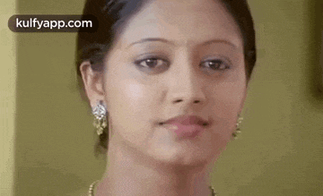 a close up of a woman 's face with a smile on her face and earrings .
