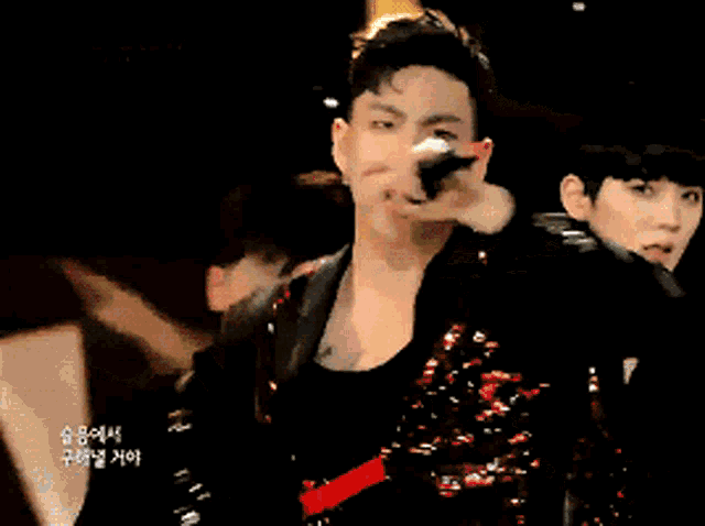 a close up of a man singing into a microphone with foreign writing on the bottom