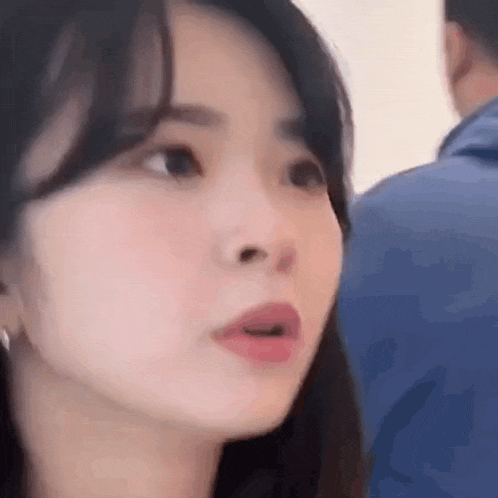 a close up of a woman 's face with her mouth open and a man in the background .