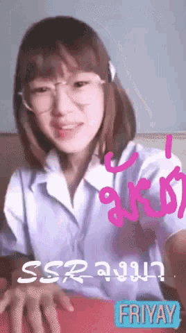 a girl wearing glasses and a white shirt is sitting on a bed .