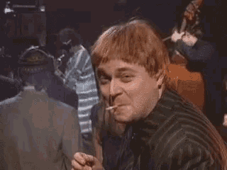 a man with red hair is giving a thumbs up sign in a crowded room .