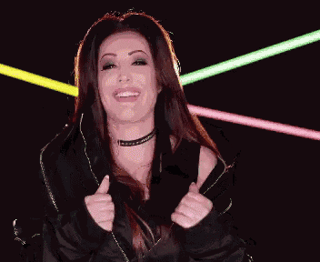 a woman in a black jacket is giving a thumbs up in front of neon lights