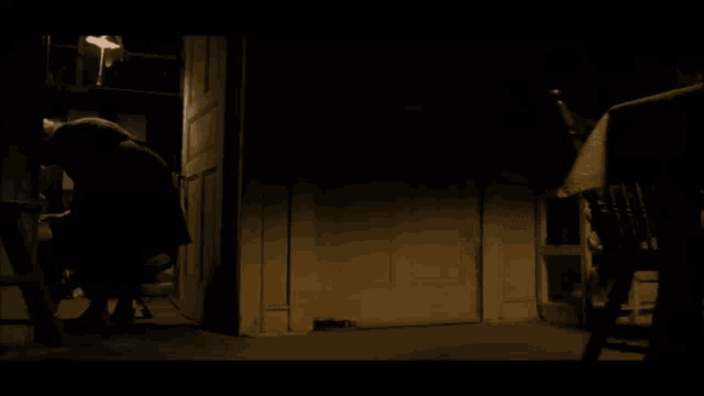 a person standing in a dark room with a chair in the foreground