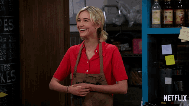 a woman wearing a red shirt and an apron that says witco on it