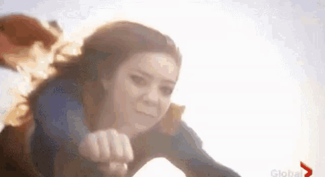 a woman is flying through the air with her fist up .