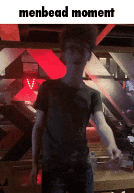 a man in a green shirt is standing in a dark room with the words menbead moment above him