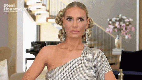 a woman is wearing a silver dress and earrings and making a funny face