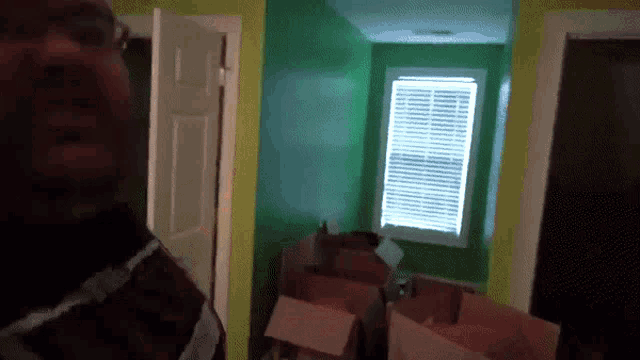 a man is standing in a room with green walls and a window