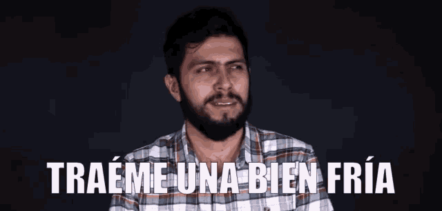 a man with a beard and plaid shirt says traeme una bien fria
