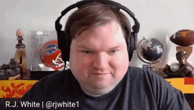 a man wearing headphones is sitting in front of a table with footballs and a globe .
