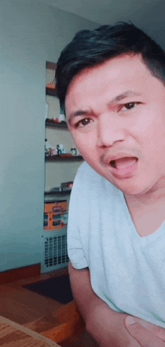 a man in a white shirt is making a funny face and sticking his tongue out