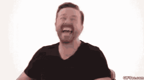 a man with a beard is laughing with his mouth open while wearing a black shirt .