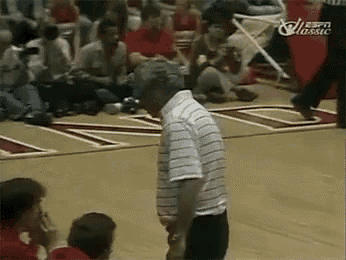 a man in a striped shirt is standing on a basketball court in front of a crowd ..