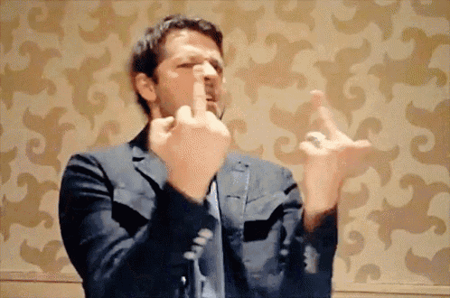 a man in a suit and tie is making a middle finger gesture
