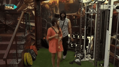 a man and a woman are standing in a gym with the words 24hr live channel on the bottom left