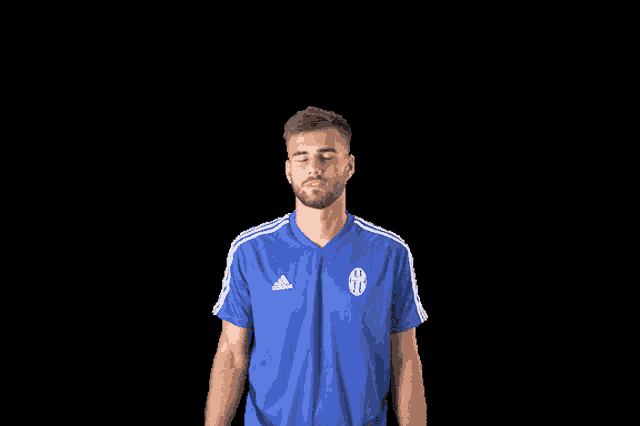 a man wearing a blue adidas shirt looks down