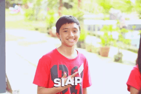 a boy wearing a red shirt that says siap