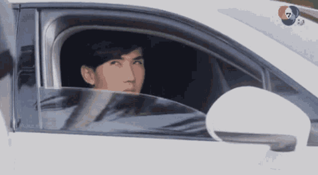 a man is sitting in a car with the number 7 on the bottom right