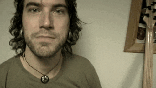 a man with a beard and a peace sign necklace