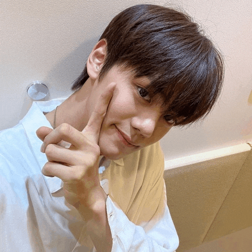a young man in a white shirt is making a funny face