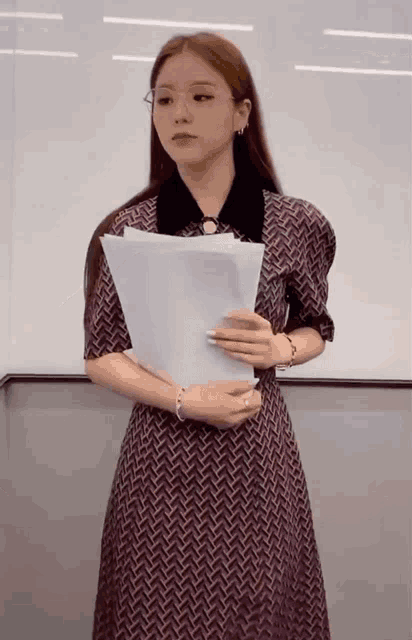 a woman in a purple dress is holding a piece of paper in her hands