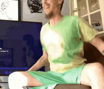 a man in a green shirt is sitting in front of a tv that says on your tv
