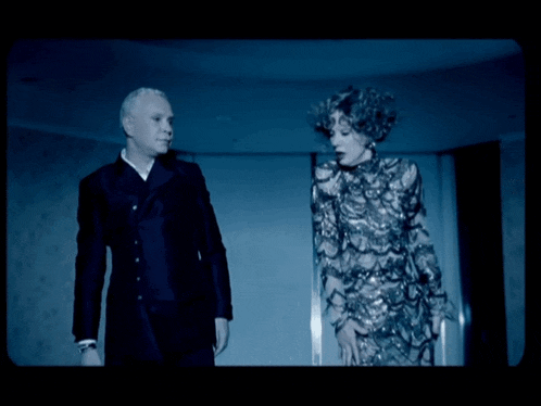 a man in a tuxedo and a woman in a dress are dancing in a dark room