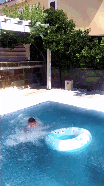 a boy is swimming in a pool with a life preserver that says kitty