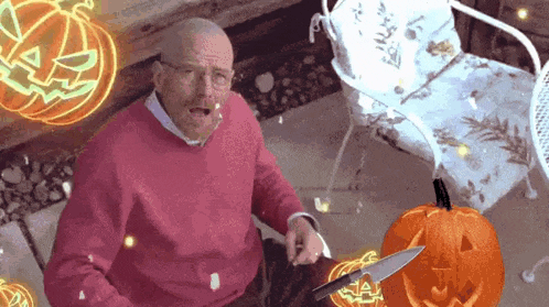 a man in a pink sweater is cutting a pumpkin with a knife