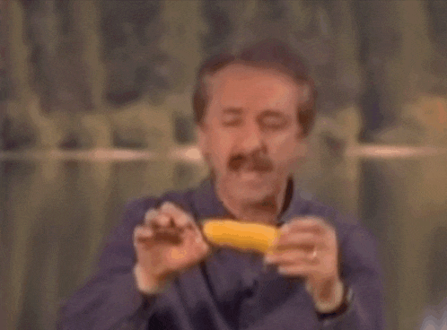 a man with a mustache is eating a corn on the cob .